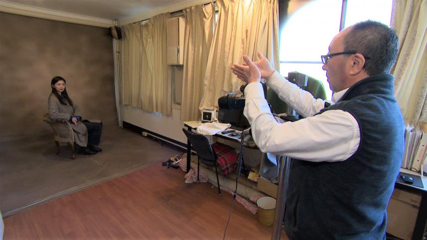 嶋写真店にて、店主の嶋さんが熊井リポーターを撮影している様子