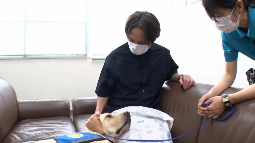 ファシリティドッグとふれあうリポーターの平野良さん