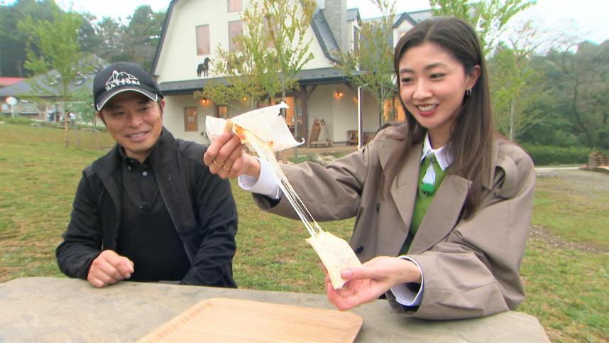テレビ写真(服部牧場の浅見さんとチーズ工房BARAKAの商品チーズブリトーを食べる熊井リポーター)