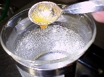 写真：冷水にジャムを滴下して煮詰め具合いを確認する