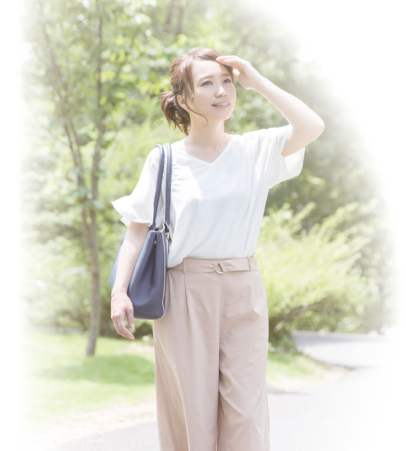 晴天の屋外に立つ半袖の女性