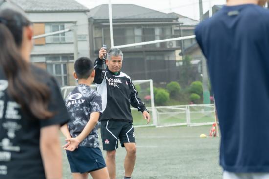 ウォーミングアップで全体へ指示をするコーチの写真