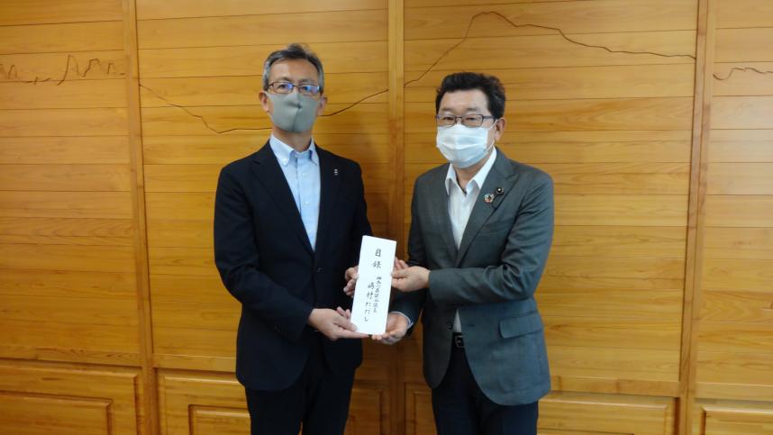 熊本県村井東京事務所長（左）に見舞金を贈呈する嶋村議長（右）の写真