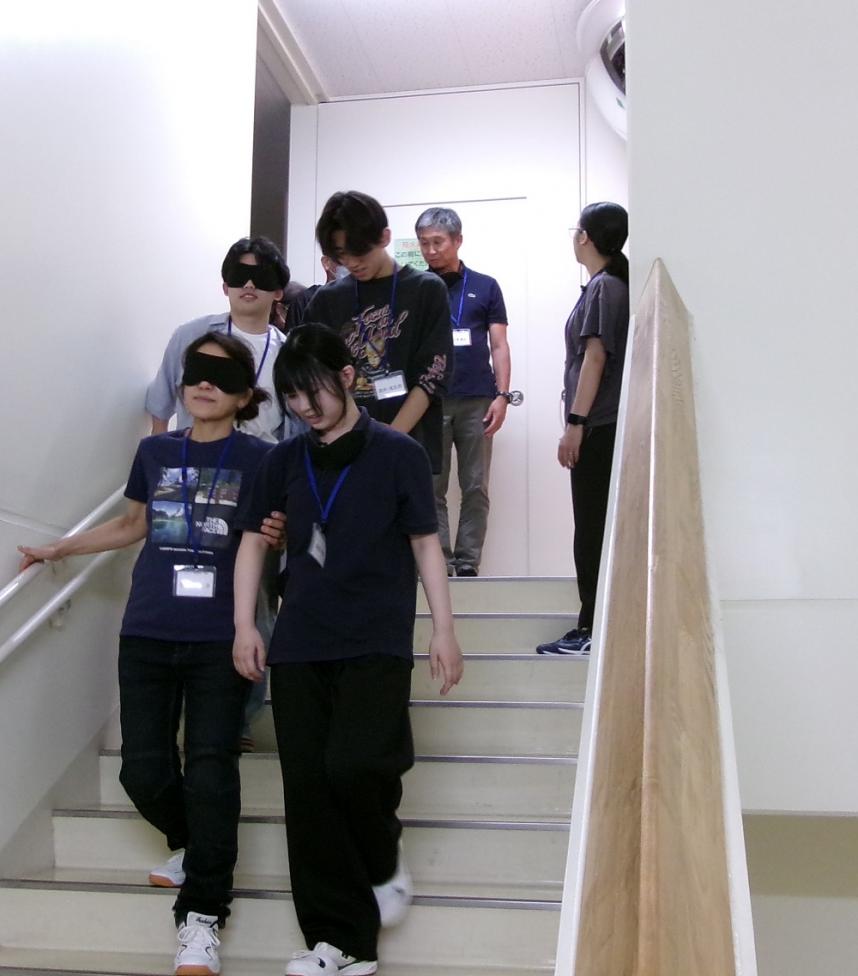 階段でアイマスクの人を、受講者が誘導している写真