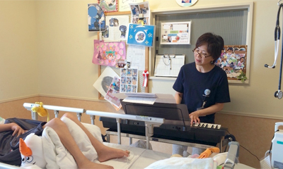 ベッドサイドで石橋さんがピアノを演奏している様子