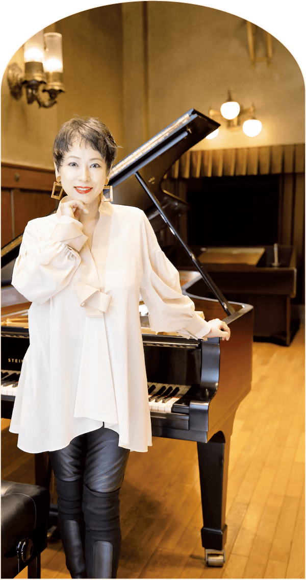 グランドピアノの前に立つ熊本マリさん